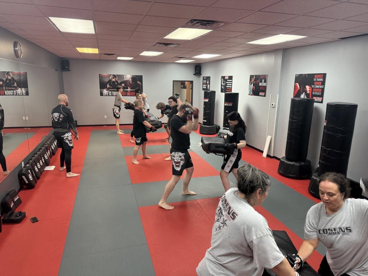 Men and women practicing controlled padwork in adult MMA class