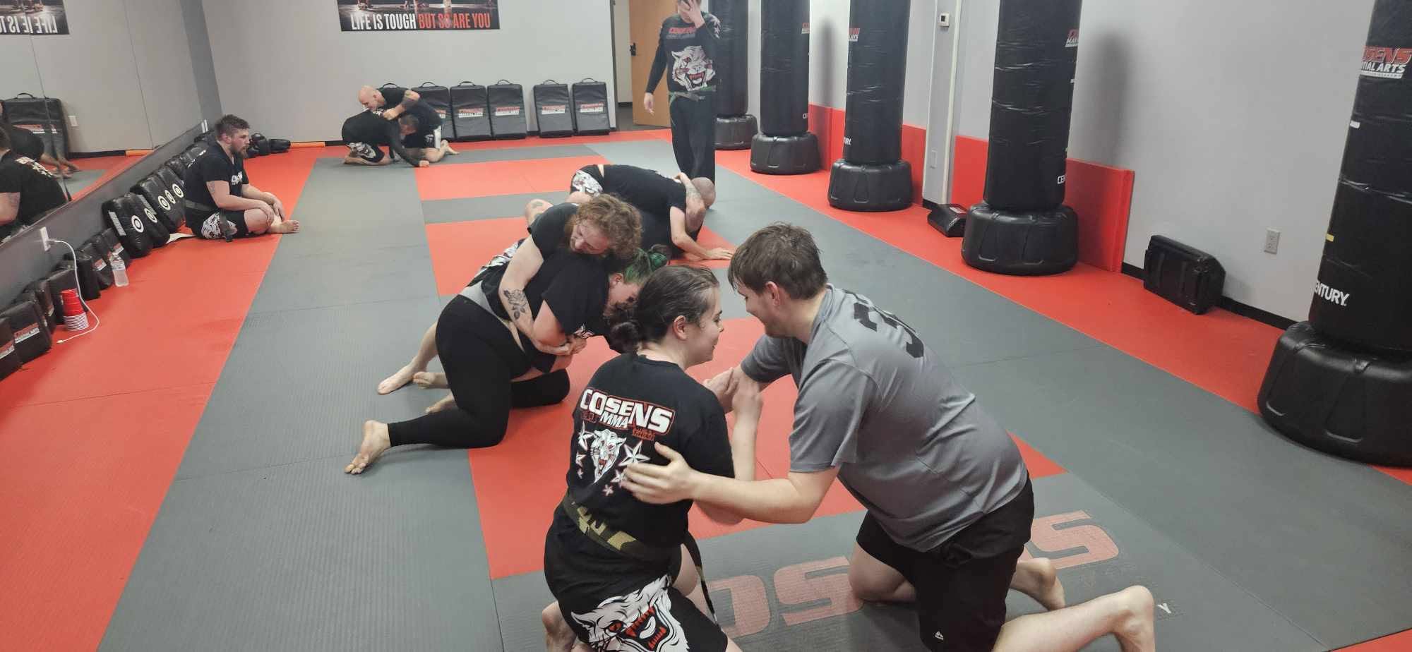 Adult students learning grappling together in a controlled class