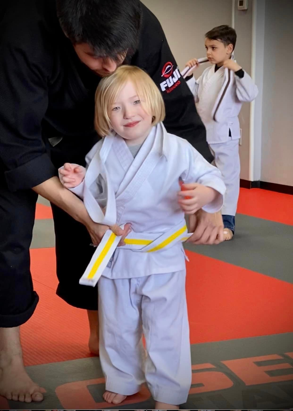 Coach helping a Tiny Ninjas student get ready for class